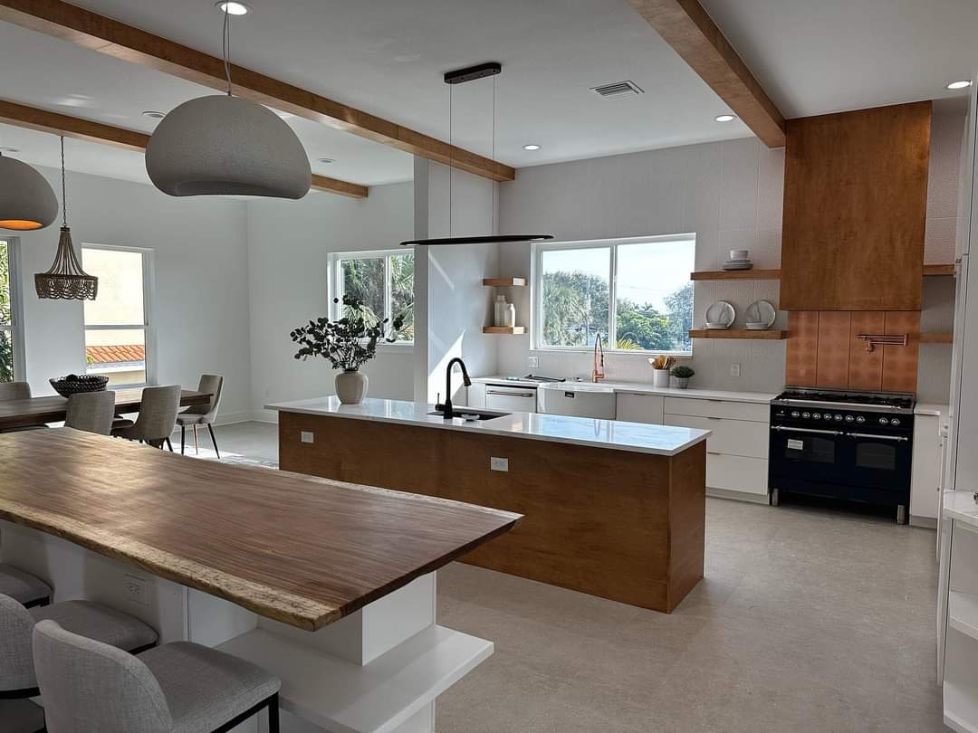 Open kitchen with wood-clad prep island, live-edge wood bar table, and floating wood shelving