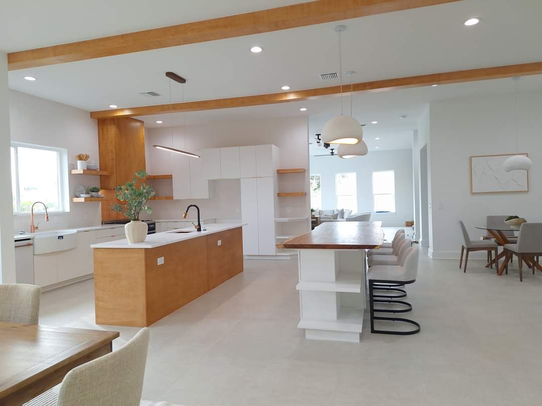 Wide view of open living and dining suite with wood ceiling beams and floor-to-ceiling windows