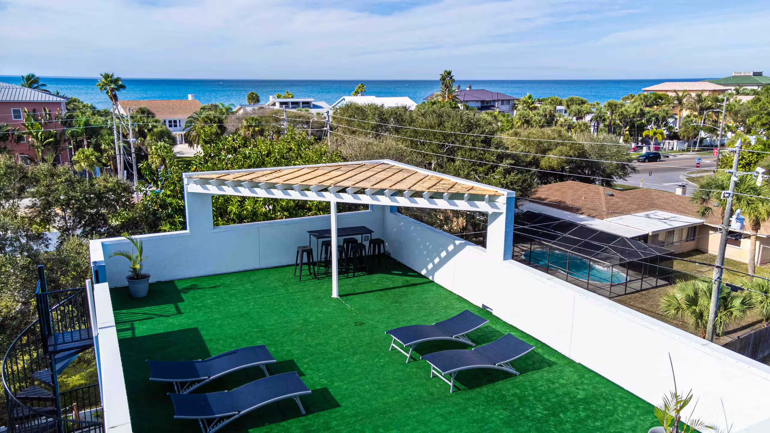 Rooftop deck with artificial turf, a wood pergola, lounge chairs, and an open Gulf of Mexico view