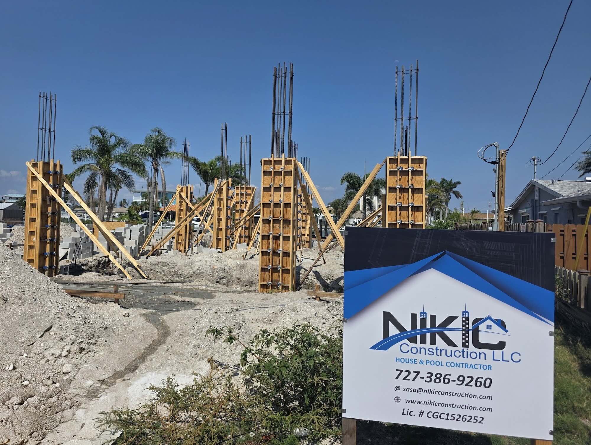 Wood formwork braced around rebar-reinforced concrete columns at a waterfront construction site