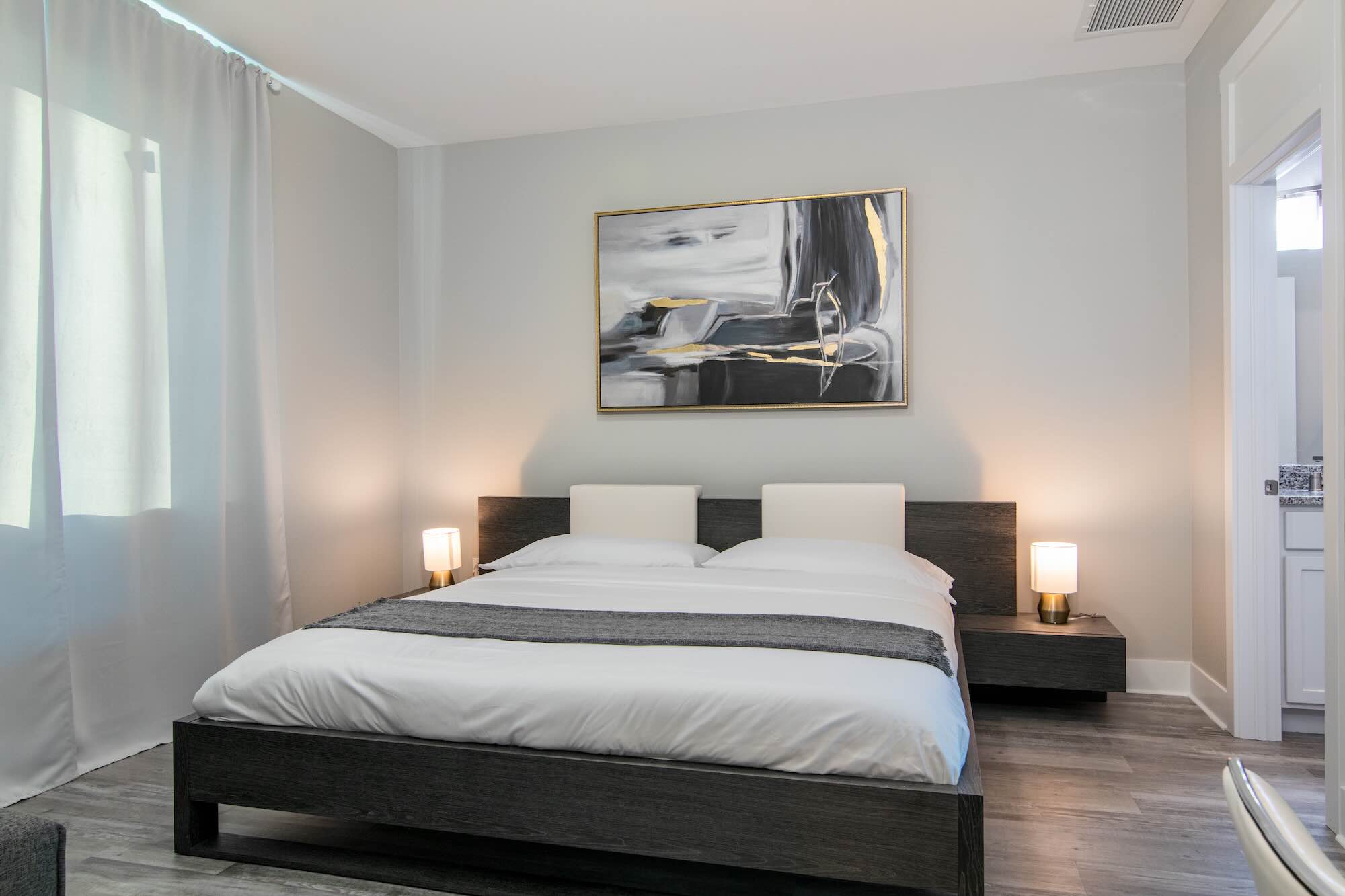 Bedroom with a dark platform bed, upholstered headboard cushions, and abstract framed artwork
