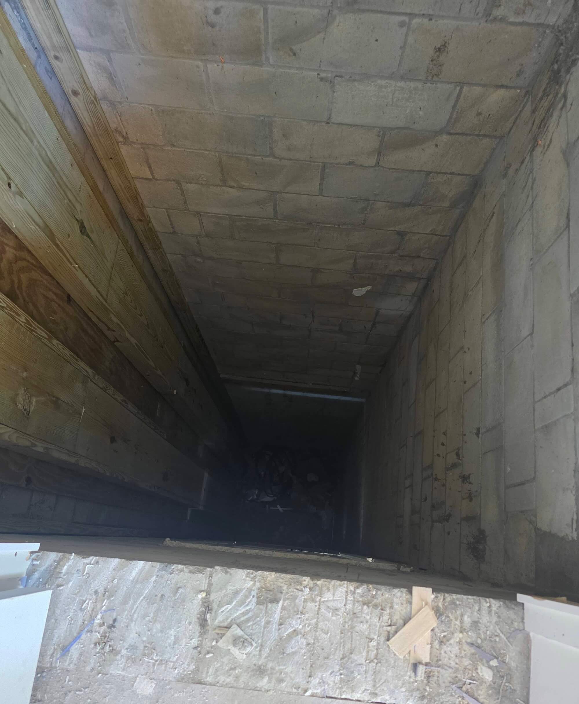 Interior view looking down a concrete block elevator or utility shaft during construction