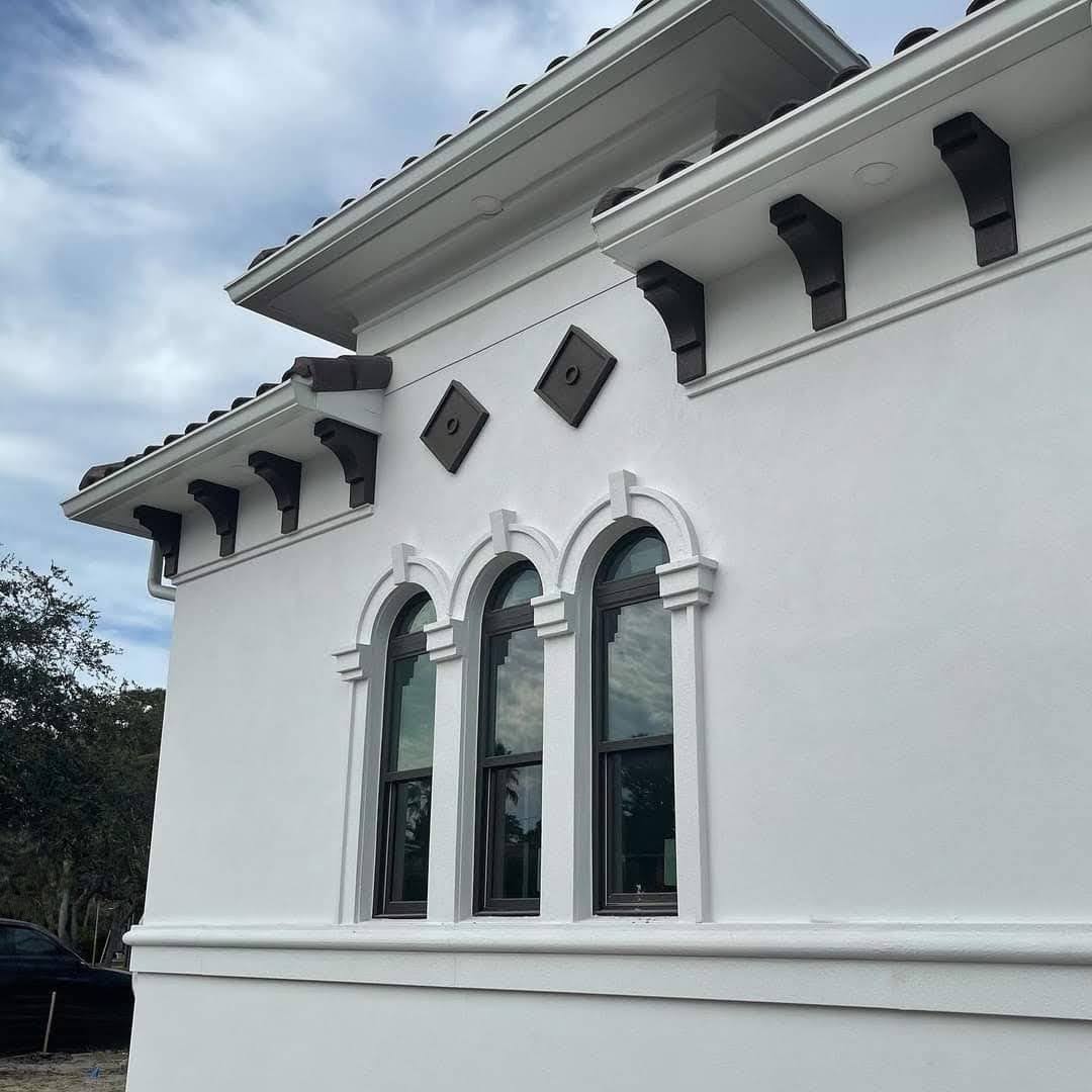 Close-up exterior detail showing triple arched windows and decorative wood corbels under a tile roofline