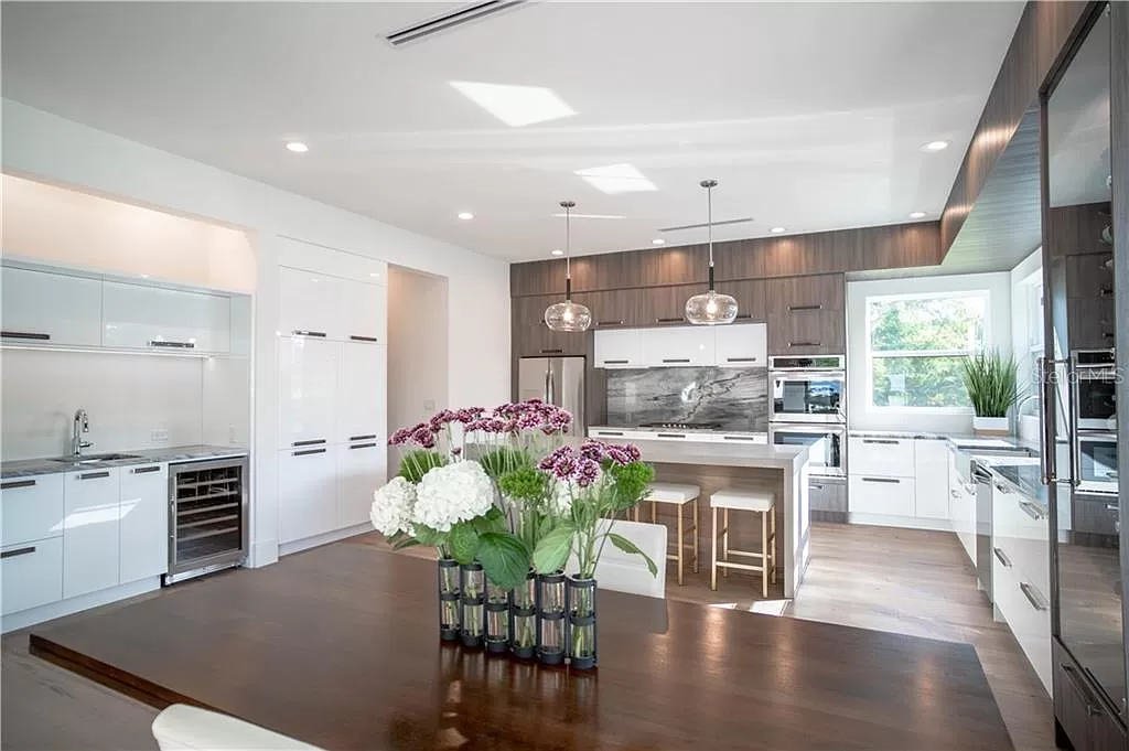 Modern kitchen island with a full-height slab stone backsplash and integrated gas cooktop, adjacent to a wood-toned wall of built-in cabinetry