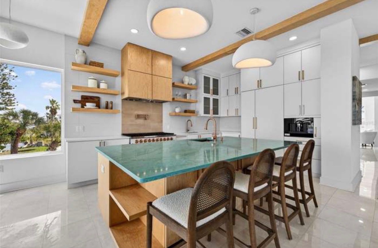 Kitchen with a teal quartz island, light wood cabinetry, open shelving, and a built-in coffee station
