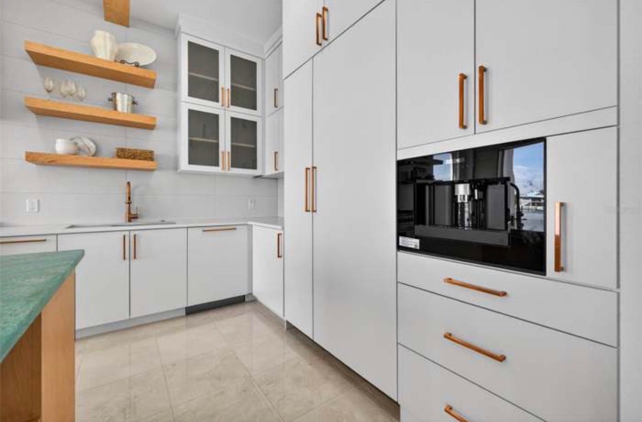 Butler's pantry with white cabinetry, copper hardware, open wood shelving, and a built-in espresso machine