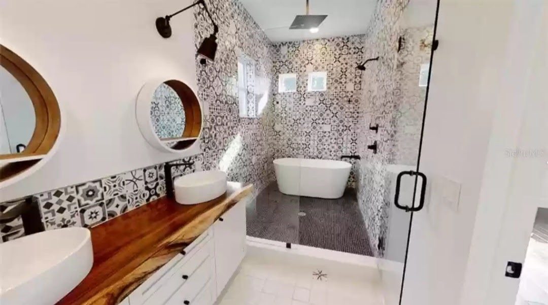 Bathroom with black-and-white patterned cement tile, live-edge wood vanity counter, and freestanding tub